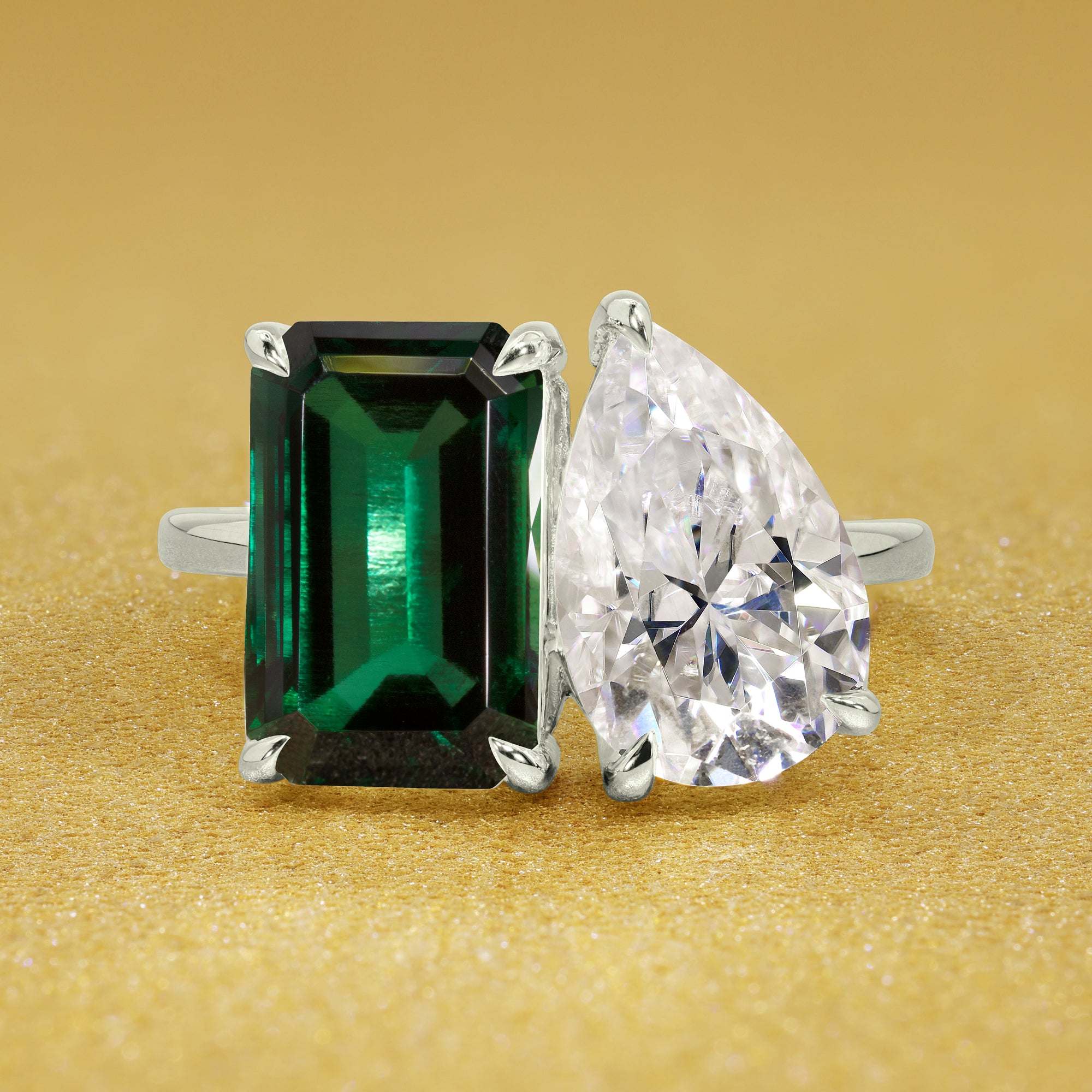 This timeless "Toi et Moi" Gemini Sleek engagement ring showcases a captivating combination of a 3.75ct lab-grown elongated green emerald and a 2.25ct pear-shaped moissanite in a minimalistic plain gold band setting. The ring is available in 14K Gold, 18K Gold, or Platinum by Earthena Jewelry of Beverly Hills.