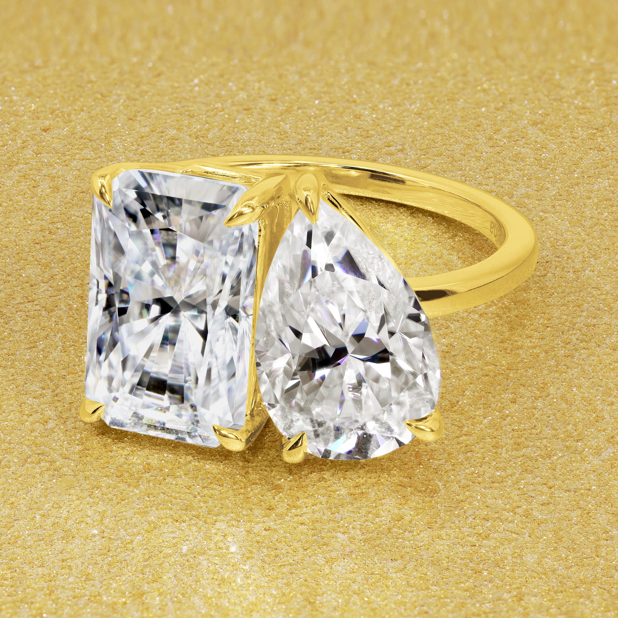 This timeless "Toi et Moi" Gemini engagement ring showcases a captivating combination of a 3.75ct elongated radiant-cut and a 2.25ct pear-shaped moissanite in a minimalistic plain gold band setting. The ring is available in 14K Gold, 18K Gold, or Platinum by Earthena Jewelry of Beverly Hills.