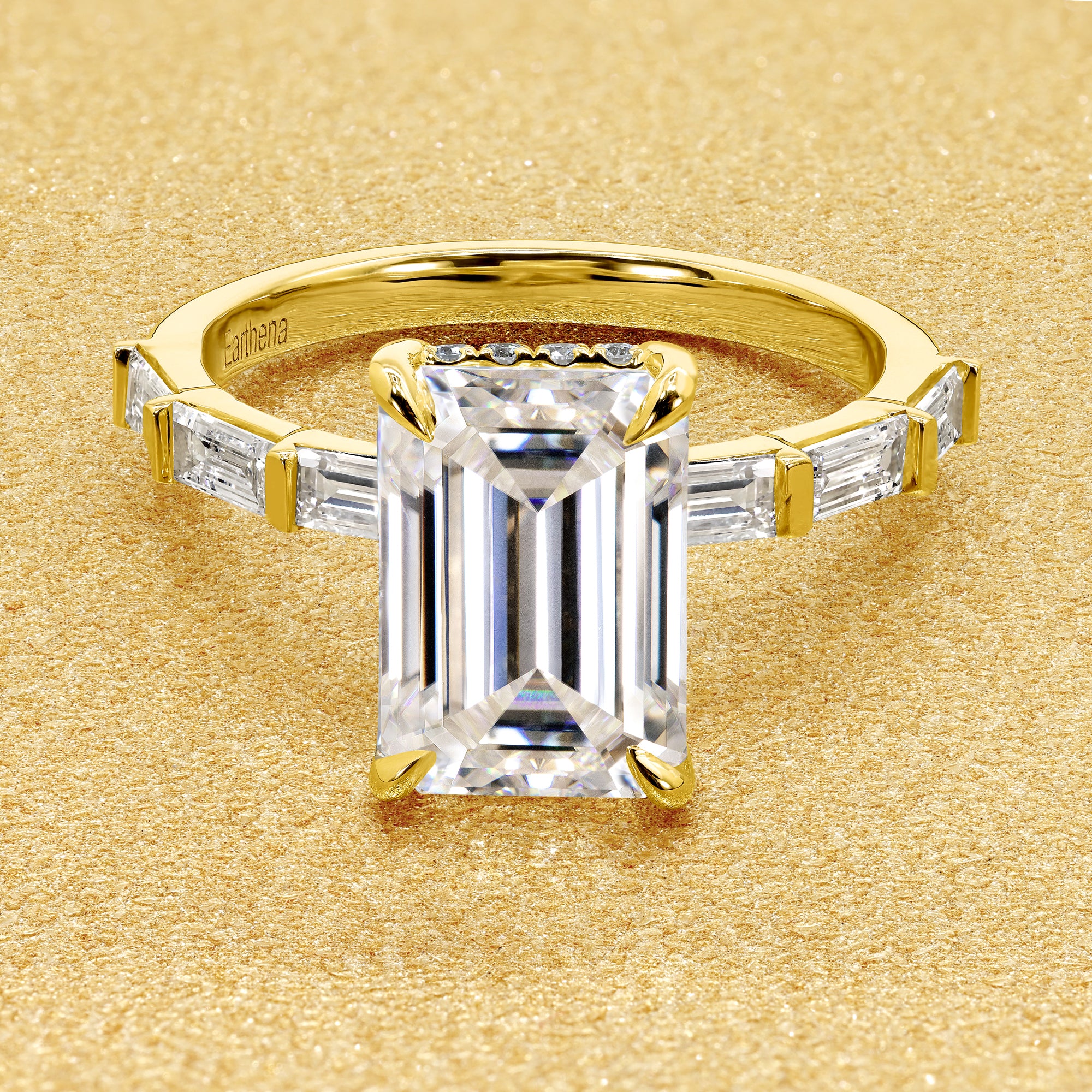 The Taylor 3ct elongated emerald-cut moissanite stone with lab-grown diamond accents set in 14K gold, 18K gold, or Platinum by Earthena Jewelry of Beverly Hills.