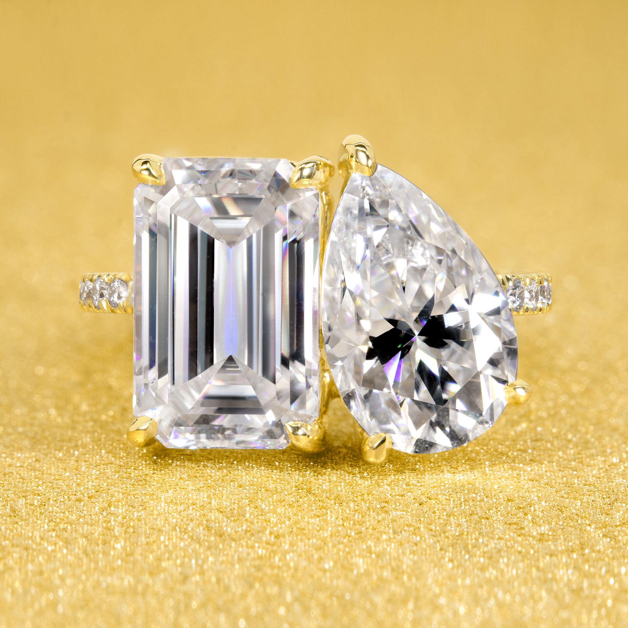 This timeless "Toi et Moi" Gemini engagement ring showcases a captivating combination of a 3.75ct elongated emerald cut and a 2.25ct pear-shaped moissanite, styled with lab-grown side diamonds. The ring is available in 14K Gold, 18K Gold, or Platinum by Earthena Jewelry of Beverly Hills.