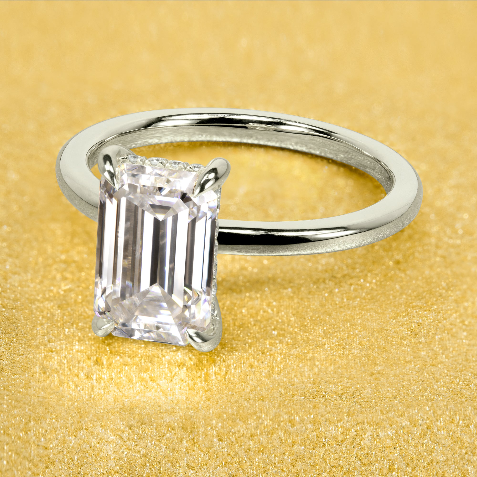 The Adara Elongated 3ct Emerald-cut Moissanite Hidden Halo Engagement Ring is a classic look with an elegant twist complemented by Lab Diamonds handcrafted in 14K Gold, 18K Gold, or Platinum by Earthena Jewelry of Beverly Hills.