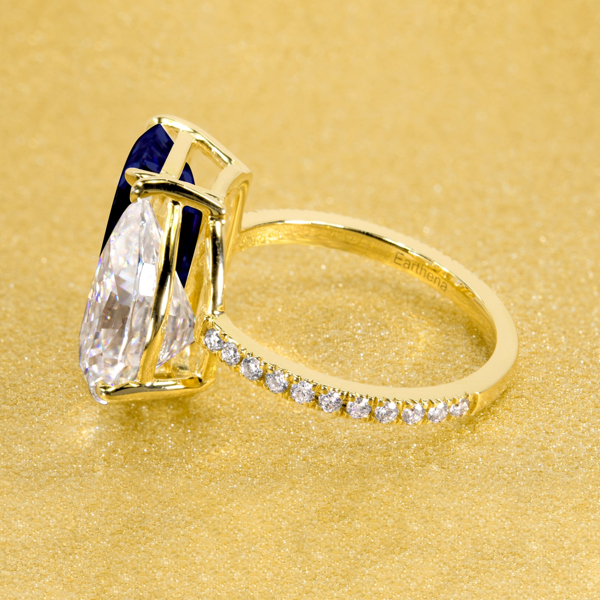 This timeless "Toi et Moi" Gemini engagement ring showcases a captivating combination of a 3.75ct lab-grown elongated emerald-cut blue sapphire and a 2.25ct pear-shaped moissanite, styled with lab-grown side diamonds. The ring is available in 14K Gold, 18K Gold, or Platinum by Earthena Jewelry of Beverly Hills.