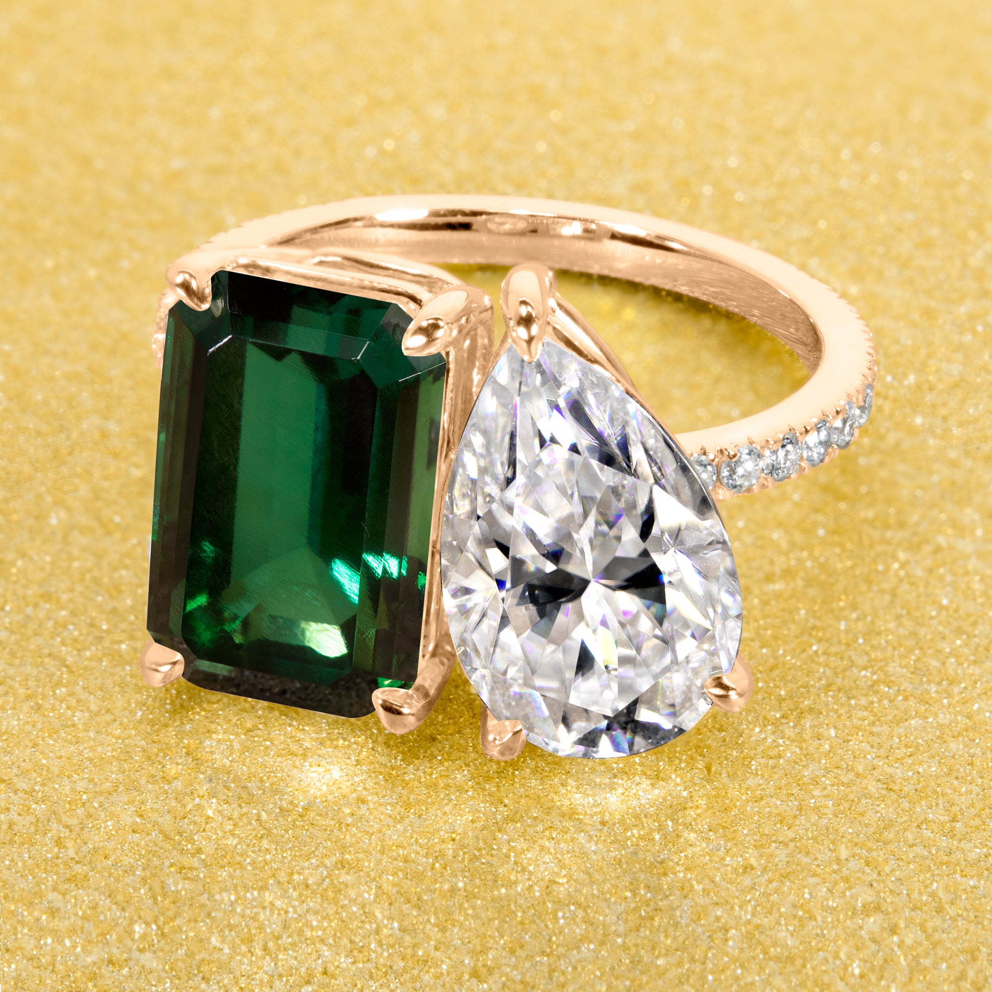 This timeless "Toi et Moi" Gemini engagement ring showcases a captivating combination of a 3.75ct lab-grown elongated green emerald and a 2.25ct pear-shaped moissanite, styled with lab-grown side diamonds. The ring is available in 14K Gold, 18K Gold, or Platinum by Earthena Jewelry of Beverly Hills.