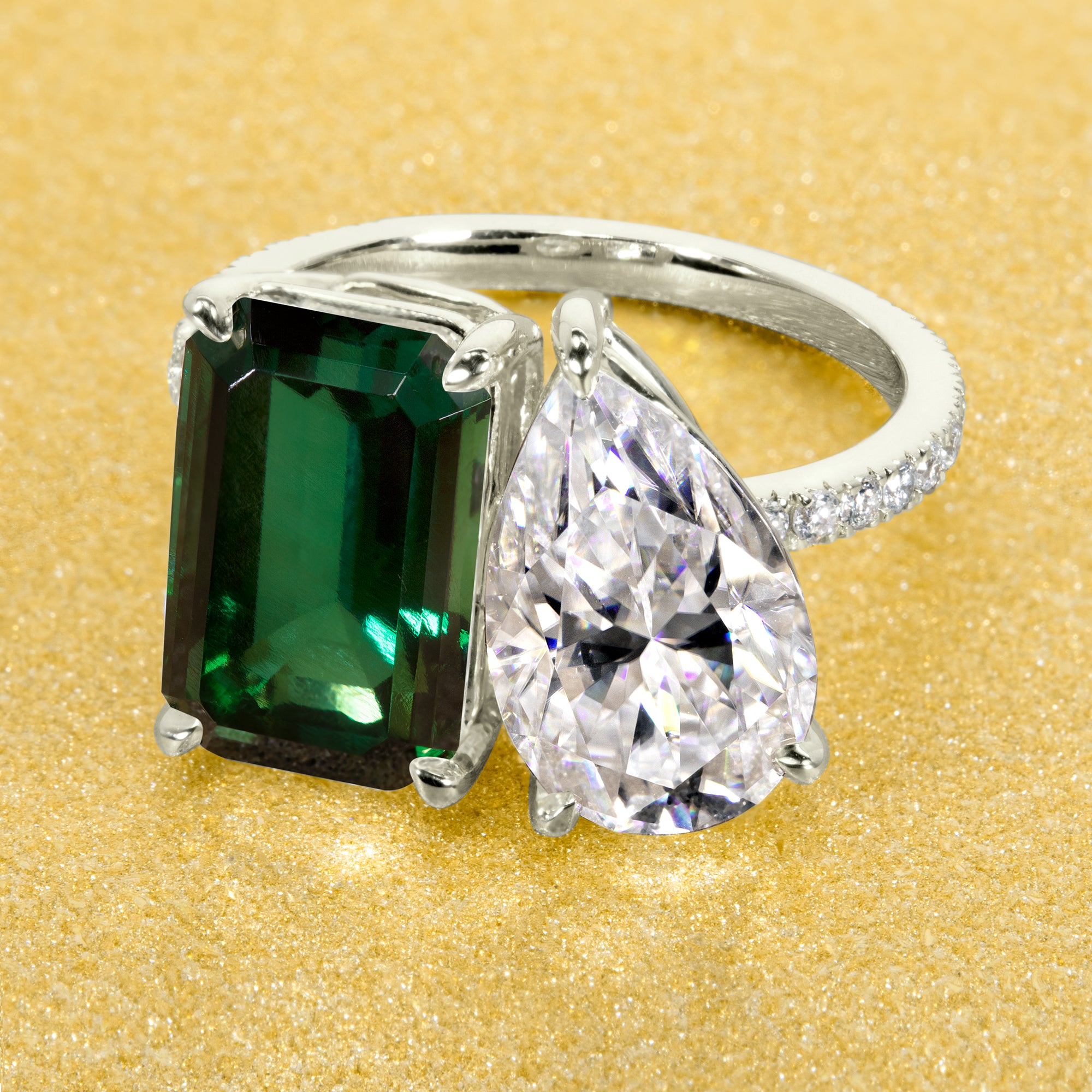 This timeless "Toi et Moi" Gemini engagement ring showcases a captivating combination of a 3.75ct lab-grown elongated green emerald and a 2.25ct pear-shaped moissanite, styled with lab-grown side diamonds. The ring is available in 14K Gold, 18K Gold, or Platinum by Earthena Jewelry of Beverly Hills.